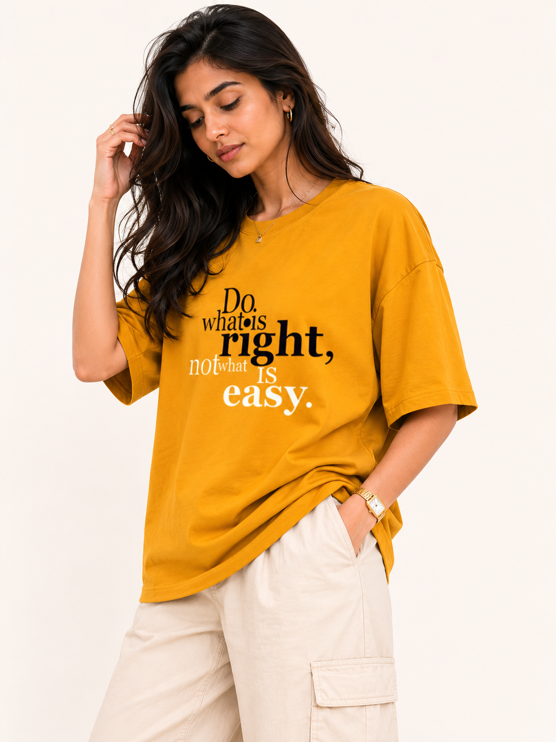 Woman wearing a mustard yellow t-shirt with a motivational quote on a plain background