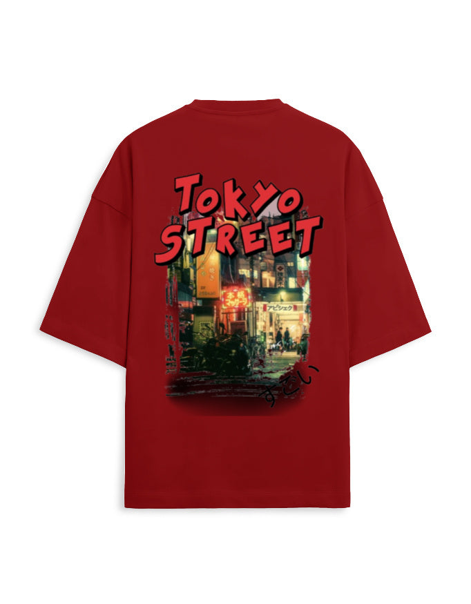 A red oversized short-sleeve t-shirt shown from the back, featuring a large graphic print of a Tokyo street scene with the text 'TOKYO STREET' in red and black.