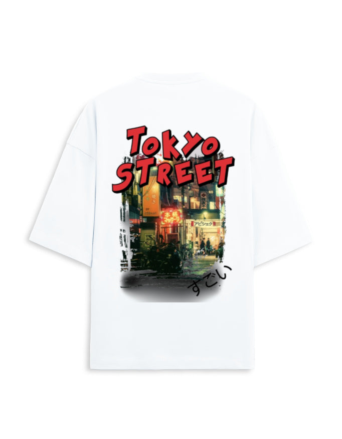 A white oversized short-sleeve t-shirt featuring a graphic print on the back. The print displays the words 'TOKYO STREET' in a bold red font above a colorful, stylized illustration of a Japanese street scene at night.