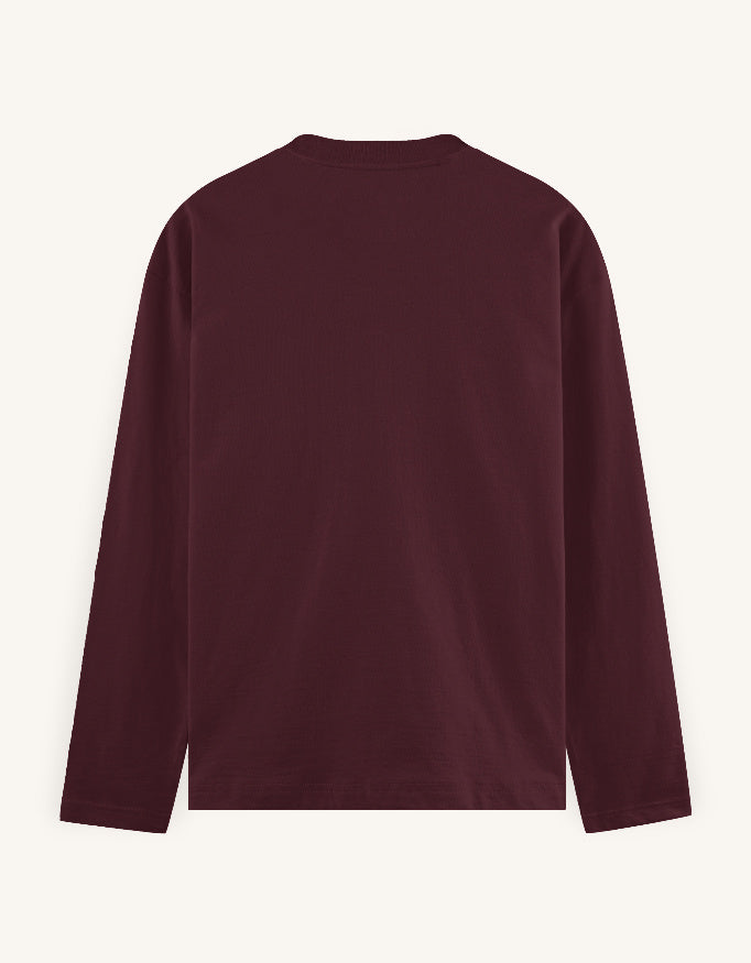 A dark burgundy long-sleeve crewneck shirt shown from the back, laid flat against a light cream background.