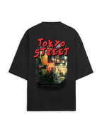 A black oversized short-sleeve t-shirt shown from the back, featuring a large graphic print with the words 'TOKYO STREET' in red and a colorful neon-lit city scene.