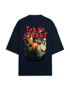 A black oversized short-sleeve t-shirt shown from the back, featuring a large graphic print with the words 'TOKYO STREET' in red and a colorful neon-lit city scene.