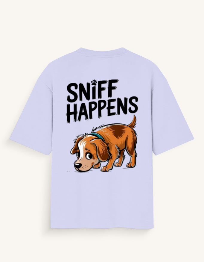 A light lavender short-sleeve t-shirt with a graphic print on the back featuring the text 'SNIFF HAPPENS' above a cartoon illustration of a brown and white dog wearing a blue collar, shown against a light cream background.