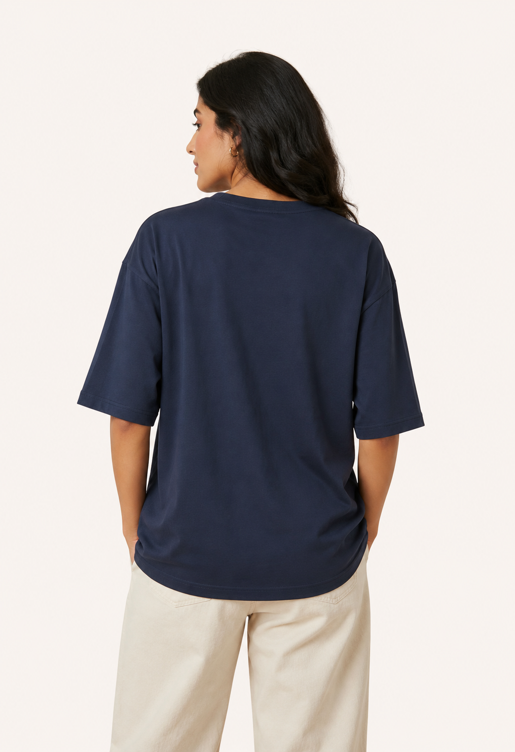Person wearing a navy blue t-shirt and beige pants on a white background