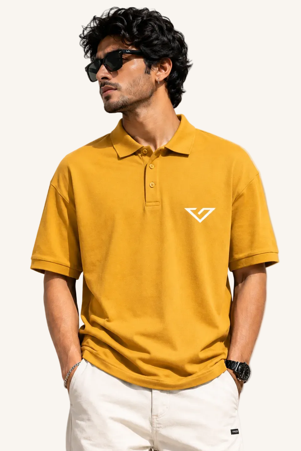 Man wearing a mustard yellow polo shirt with a logo against a plain background