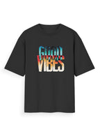 A black short-sleeve t-shirt with a colorful graphic text print reading 'GOOD VIBES' in a retro gradient font, displayed on a clean white background.