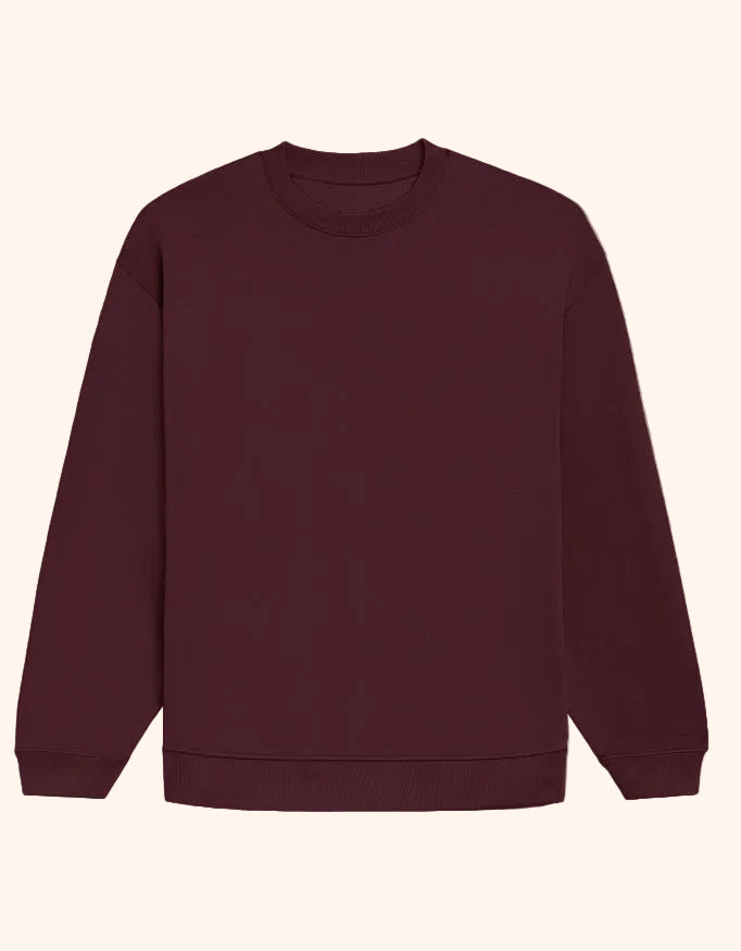 A plain crewneck sweatshirt in a deep burgundy color, laid flat against a solid taupe background.