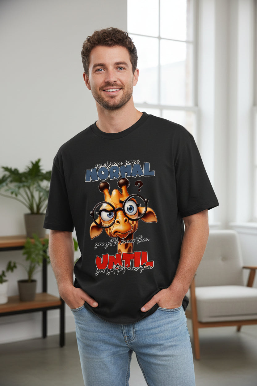 A black short-sleeve t-shirt with a graphic of a cartoon giraffe wearing glasses, with the text 'normal' in blue and 'UNTIL' in red, displayed on a light off-white background.