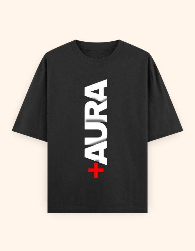 A black short-sleeve t-shirt with a vertical white 'AURA' text graphic and a small red cross accent on the front, displayed against a light cream background.