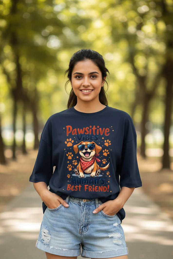 A navy blue short-sleeve t-shirt with a colourful graphic of a cartoon dog wearing sunglasses and a red bandana, surrounded by paw prints and the text 'Pawsitive Vibes Human's Best Friend!'.
