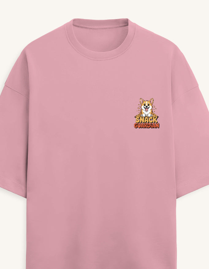 A pink short-sleeve crewneck t-shirt featuring a small graphic on the left chest with a cartoon dog and the text 'SNACK GUARDIAN'.
