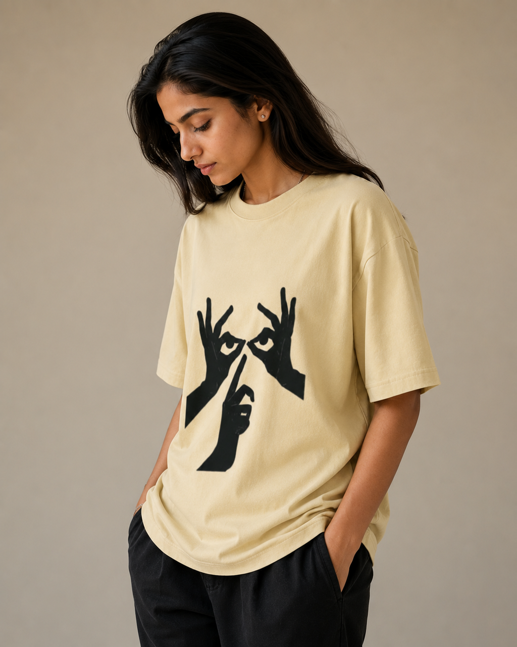 Woman wearing a beige t-shirt with black graphic design on a neutral background