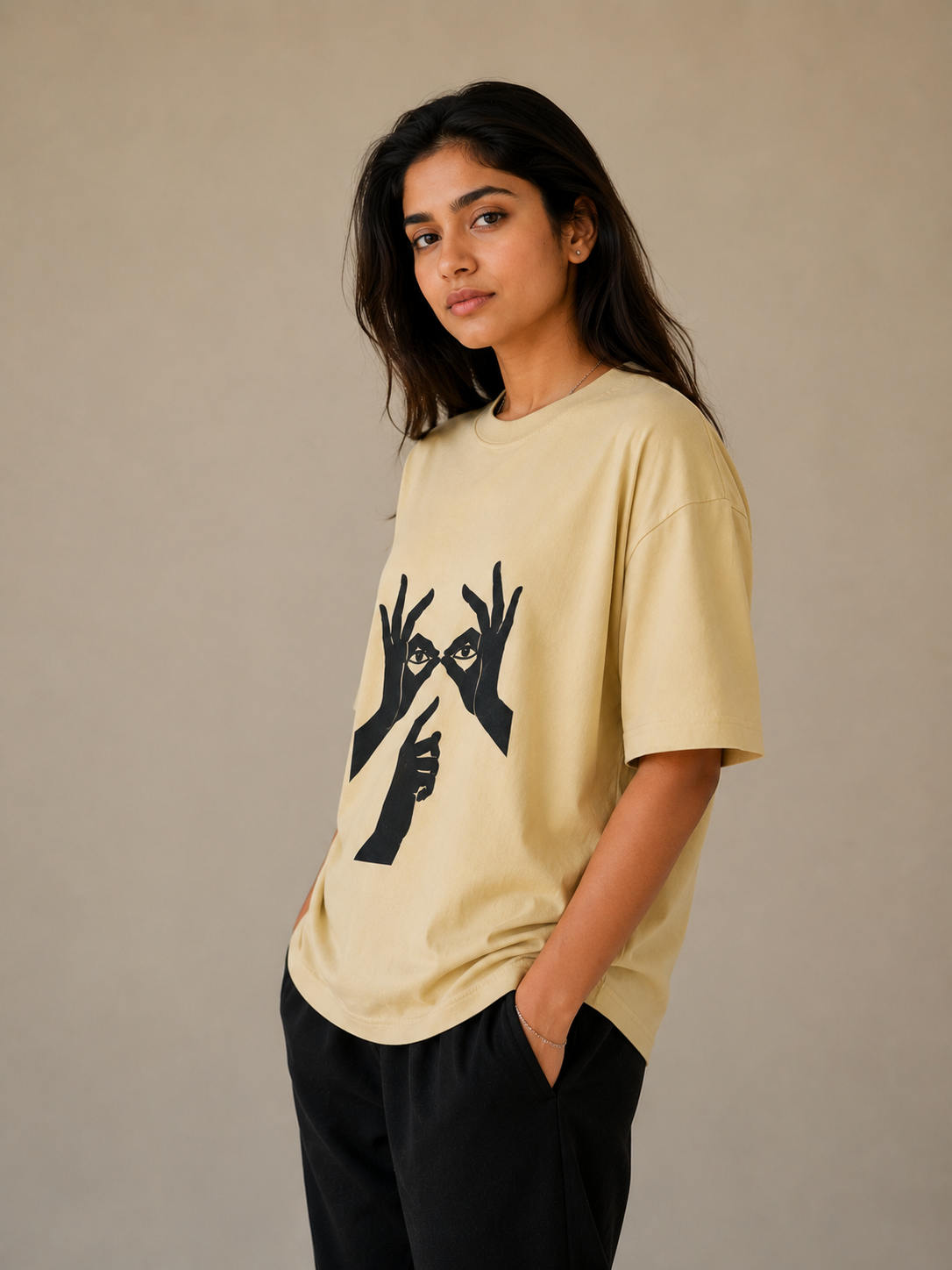 A woman wearing a light yellow t-shirt with black graphic design on a beige background