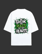 A white short-sleeve t-shirt with a large graphic print on the back featuring the text 'WE BREAK THE RULES BUT NOT HEARTS' in a graffiti-style font over a green paint-splatter background.
