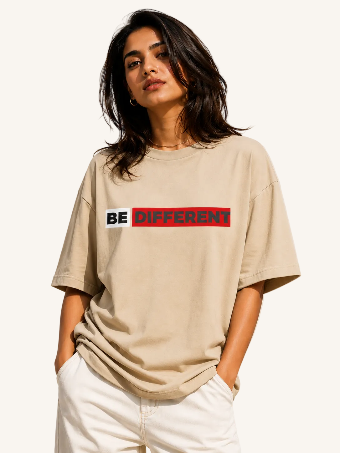 Woman wearing a beige t-shirt with 'BE DIFFERENT' text on a plain background