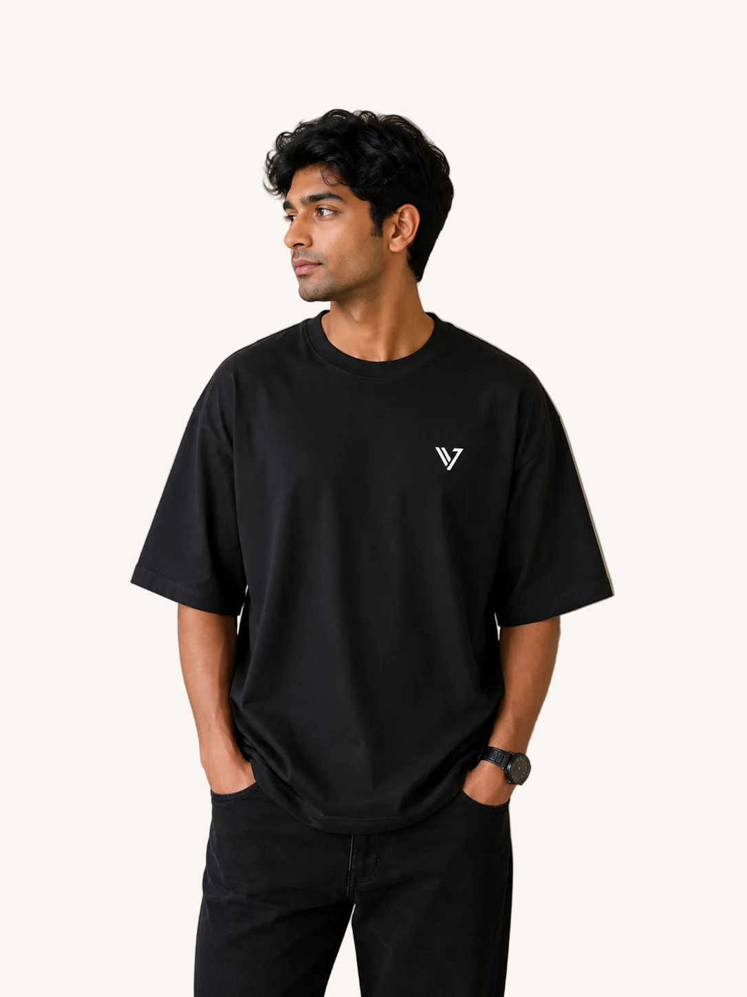 Man wearing a black t-shirt with a logo against a beige wall