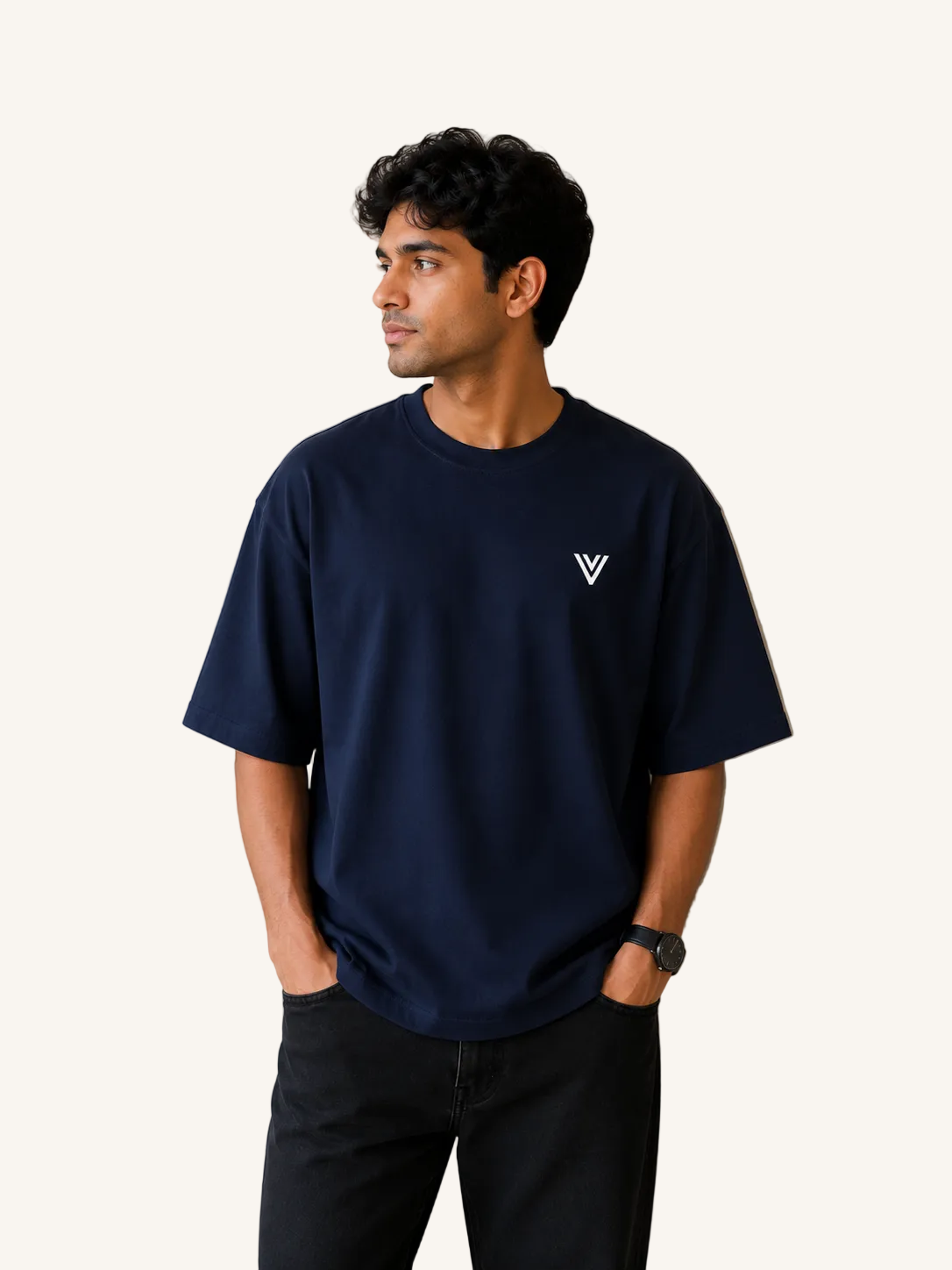 Man wearing a navy blue t-shirt with a white logo against a beige wall.
