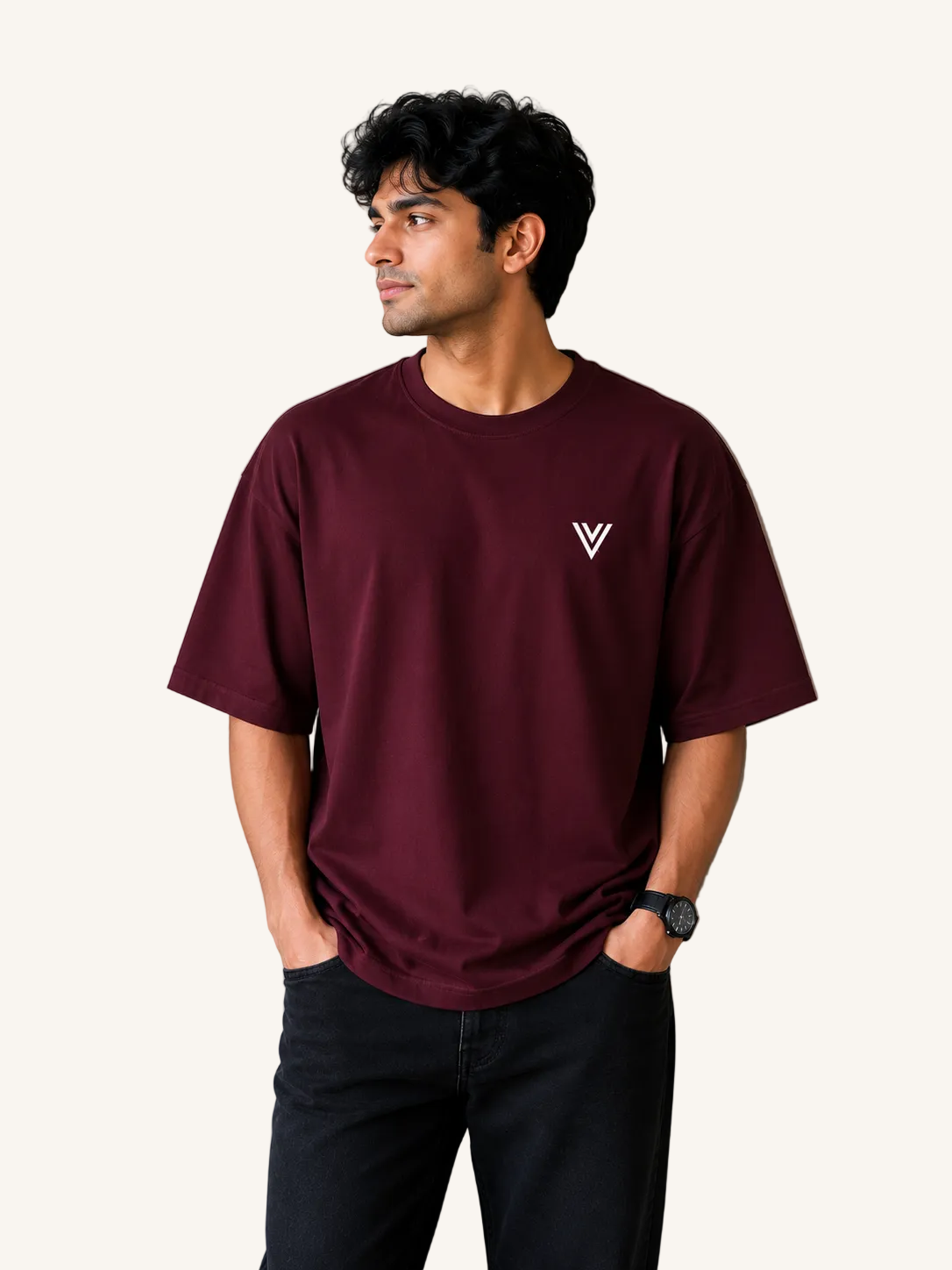 Man wearing a maroon t-shirt with a logo against a beige wall