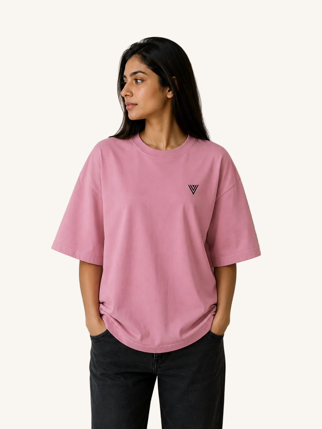 Person wearing a pink t-shirt with a small logo on a plain background